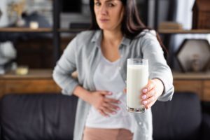 A lady in pain holding a glass of milk